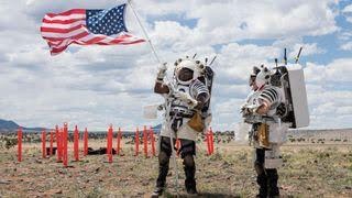 NASA astronaut Andre Douglas raises an American flag as NASA astronaut Kate Rubins looks on during their first simulated moonwalk