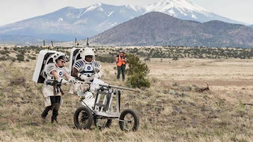 NASA astronauts named Kate Rubins and Andre Douglas can be seen pushing a cart loaded with tools that are to be used on the lunar surface in San Francisco Volcanic Field