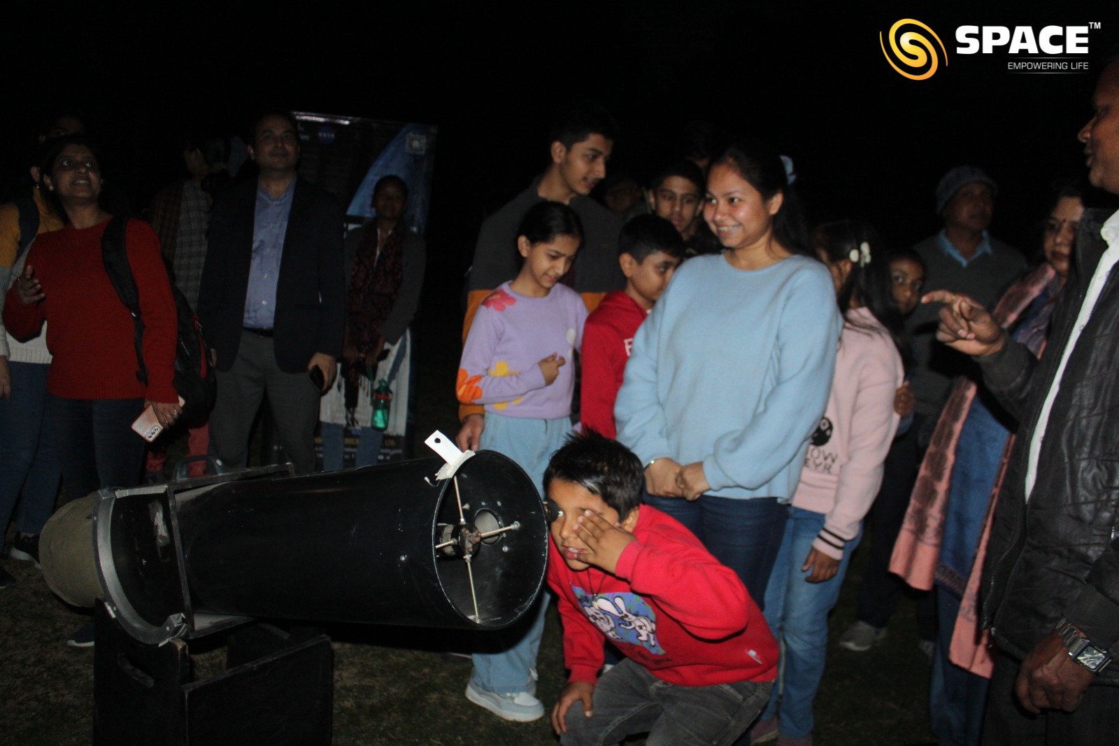 People observing celestial objects through Dobsonian telescope